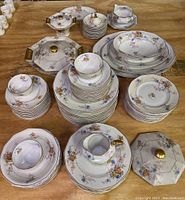 Overall view of multiple china pieces including plates, cups, saucers and serving dishes arranged on table