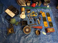 Wide view of all items laid on blue tarp including tins, tools, lamps, and other gadgets as described.