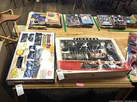 Two boxed vintage train sets on a wooden table. Left is Santa Fe Express, right is Pioneer Early American Railroad.