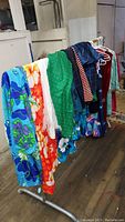 Multiple vintage and ethnic clothing items on rack including tropical floral dresses and shirts