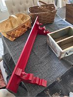 Two woven wood baskets, red ornate floating shelf, and wooden storage/display box on a cloth-covered surface.