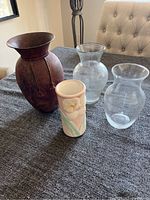 Overview of four flower vases on table showing different materials and styles: metal, glass, ceramic
