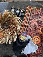 Overview of holiday decorations including the wreath, table runners, carved wooden figurines, pumpkin candle holder, and bat costume pieces on a table