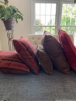Side view of five throw pillows stacked with striped pillows in front and other pillows behind on couch.