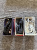 Top view of three pairs of women's shoes in their boxes showing black high heels, slingbacks, and slip-ons.