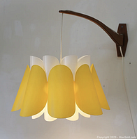 Full view of lamp hanging from swivel teak arm against white wall