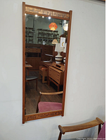 Full front view of rectangular teak wall mirror with copper etched trim on top and bottom