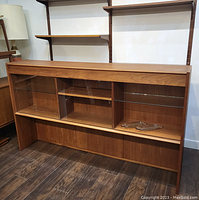 Front left angle view of teak glass display cabinet showing overall structure and shelving