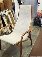 Assembled chair showing curved teak frame and fabric sling seat in workshop setting