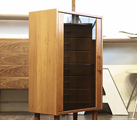 Front angle view showing closed smoked glass door, teak finish, and tapered legs