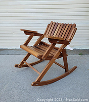 Front-left view of wooden rocking chair showing slatted seat and armrests.