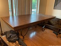 Rectangular dining table with wooden top and visible natural wood grain placed in a room by a window