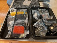 Open zippered case showing foam-lined compartments filled with floaty hand grip, mounts, screws, cable and camera