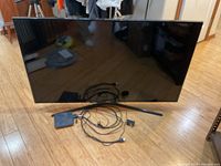 Front view of Samsung 48-inch TV with stand and cables laid out in front.