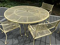 Three-quarter view of round metal table top and three chairs on deck