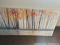 Frontal image of large canvas showing abstract birch tree forest with autumn leaves in orange, yellow, gray and black tones.