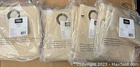 Four Eclipse Madison curtain panels packaged in clear plastic, showing light khaki color and circular grommet tops visible on each panel.