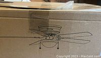 Cardboard box featuring a line drawing of the ceiling fan including five blades and a dome-shaped light fixture beneath the motor housing.