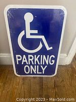 Photo shows one new metal handicapped parking sign with blue background, white wheelchair symbol, and 'PARKING ONLY' text.