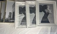 Five picture frames wrapped mostly in bubble wrap placed on a white surface, showing 3 frames appear white and 2 have a gold tone.