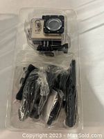 Top-down photo of the sports camera in a waterproof case along with mounting accessories packed separately below in a clear plastic mold.