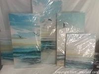 Five canvas wall art panels depicting coastal scenes with ocean waves, seagulls, and sky. Panels are wrapped in plastic and arranged to show the full beach scene.