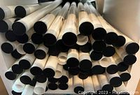 Photo showing rolled canvas prints stored horizontally in a box or container, tube ends visible.