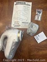 Eureka Clothing Shaver with user manual, accessory bag, and power cord laid out on wooden surface.