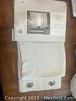 Exclusive Home blackout grommet curtain panels in packaging, folded showing fabric texture and color.