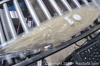 One set of silk faux pampas grass packaged in plastic wrapping with label visible, placed on roller conveyor.