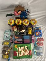 Photo of entire toy lot showing Ready2Robot blaster, capsules, plush keychains, table tennis set, toy cars, party poppers and more