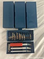 Four blue plastic cases of Exacto knife sets, three closed single case, one open showing blades and three handles.
