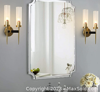 Photo of two identical wall lamps mounted on white wall, with transparent cylindrical glass shades and warm light bulbs, shown flanking a decorative mirror in a modern interior.