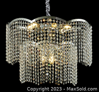 Illuminated crystal pendant light chandelier with nine bulbs and cascading crystal strands on chrome frame, photographed against black background.
