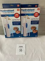 Front view of two boxed Hydroblast Cordless Water Flosser sets showing product images and features including 1600 bursts and multiple pressure settings.