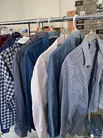 Photo showing 6 shirts hung on a rack: dark blue/gray checkered, blue denim, light pink, blue chambray, black/white checkered, gray shirt.
