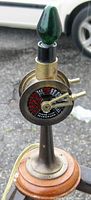 Close-up of the antique brass ship engine room telegraph lamp showing dial and levers, mounted on stepped wooden base