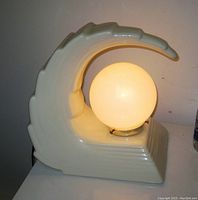 Side view of the cream ceramic wave lamp illuminated with white globe light.