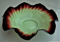 Top view of the ruffled, circular footed fruit bowl showing the pale green vaseline glass center blending to ruby-colored rim.