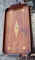 Top-down photo of rectangular wooden tray showing Art Deco style inlay with floral motifs and handles on short sides.