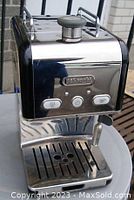 Front view showing the stainless steel and black aluminum body with control buttons and frother