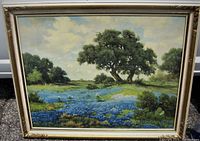 Front view of framed landscape art print featuring Texas bluebonnets and trees with partly cloudy sky in background.