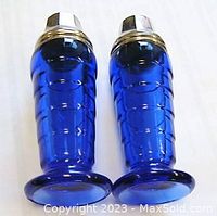 Front side view of cobalt blue glass salt and pepper shakers, showing the embossed geometric Art Deco pattern and metal tops.