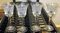 Front view showing the set of four crystal claret wine glasses with deep cut designs, highlighting the star pattern on base and intricate bowl faceting.