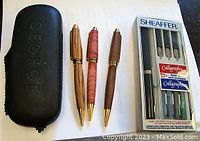 Three vintage wooden pens and a boxed Sheaffer calligraphy set with pen and nibs.