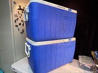 Two blue Coleman coolers stacked on top of each other, showing overall condition and relative size.
