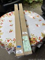 Two long rectangular boxes containing the shades on a floral tablecloth outdoors.