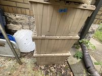 Stacked beige plastic storage totes outdoors showing normal age wear and dirt.