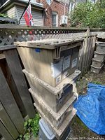 Four stacked beige plastic storage totes with attached lids, showing exterior and top details.