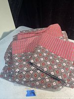 Photo showing folded queen size bed sheets with geometric and striped patterns, including fitted sheet, flat sheet, and pillowcases.